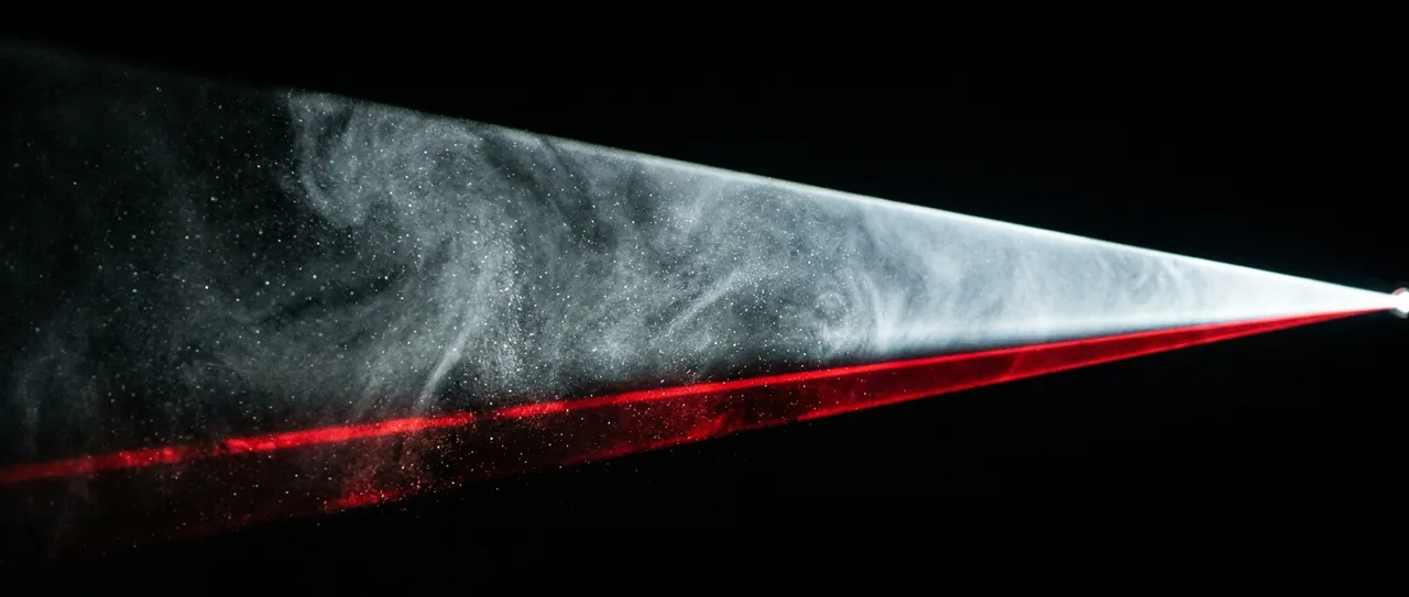 A cinema projector beam cutting through haze, edged with red light.